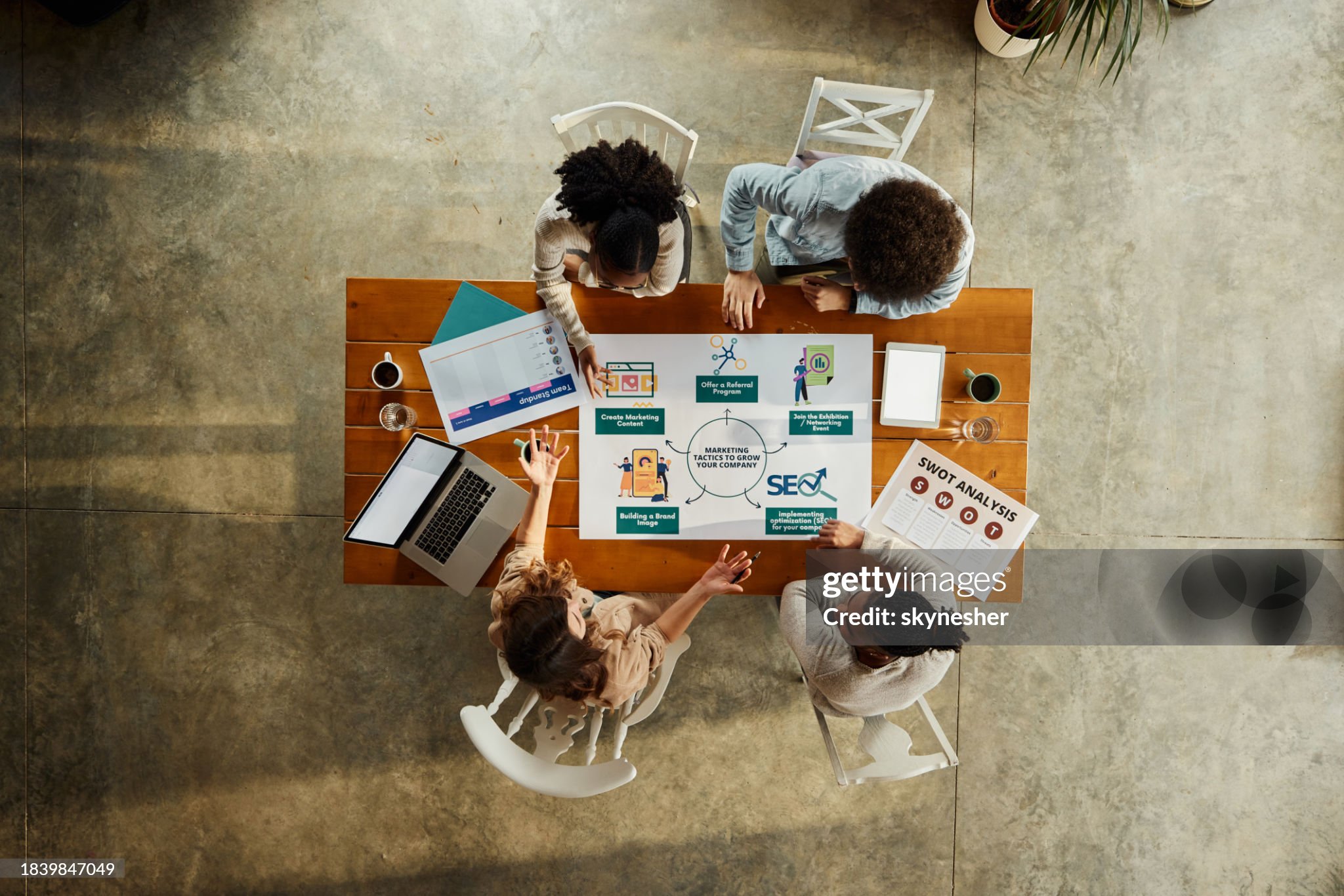 High angle view of team of creative people talking while analyzing strategies of digital marketing in the office. Copy space.